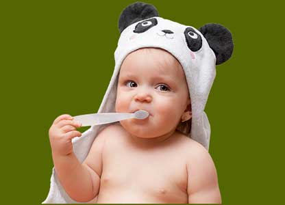 baby wearing a panda ears towel and chewing on a toothbrush